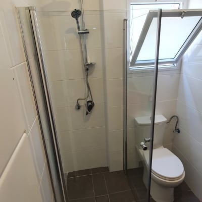 מקלחון זכוכית עם ראש מקלחת וכיור שירותים