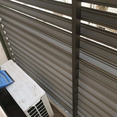 יחידת מזגן ליד גדר מתכת אפורה