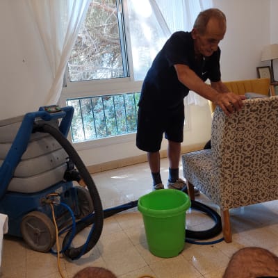 אדם מנקה כורסה עם מכונת ניקוי ושואב אבק