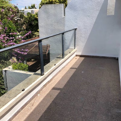 מרפסת עם מעקה זכוכית וקיר צבוע בלבן