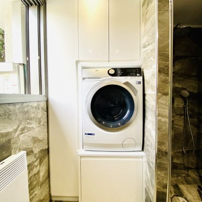 מכונת כביסה לבנה בתוך ארון בחדר אמבטיה