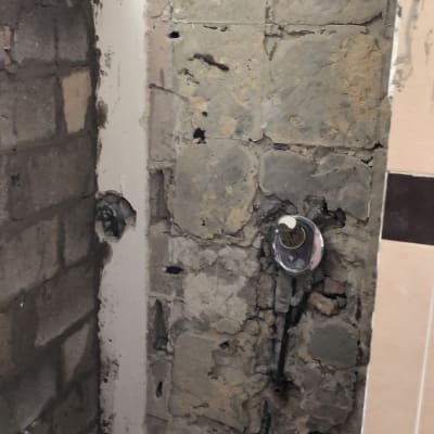 קיר חשוף עם צנרת חשמל ושקע במהלך שיפוץ