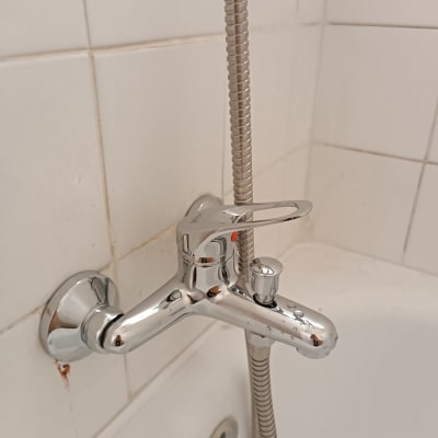 ברז כרום עם צינור במקלחת על רקע שיש לבן