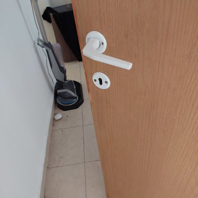 ידית דלת לבנה על דלת עץ פתוחה