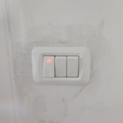 מתג חשמל עם נורית חיווי אדומה על קיר לבן