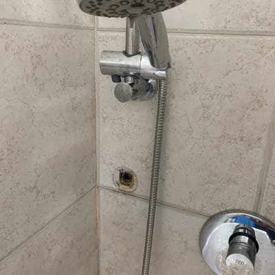 ראש מקלחת וכפתור מים על קיר אריחים