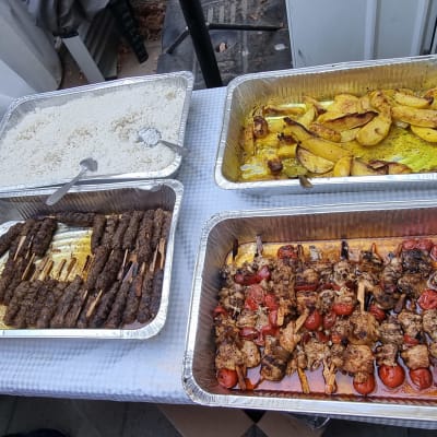 מגשי אוכל עם קבב, שיפודים, אורז ותפוחי אדמה.