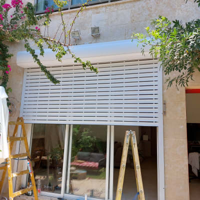 תריס אלומיניום לבן מותקן על חלון זכוכית גדול