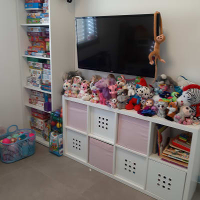 מדפים עם משחקי קופסה, קוביות אחסון עם צעצועים, טלוויזיה תלויה