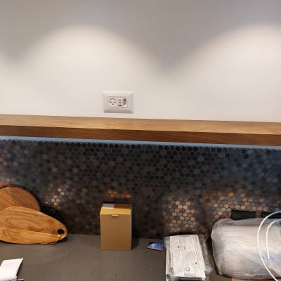 מדף עץ מותקן על קיר עם אריחים כהים