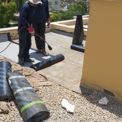 עובדים אוטמים גג עם יריעות ביטומניות