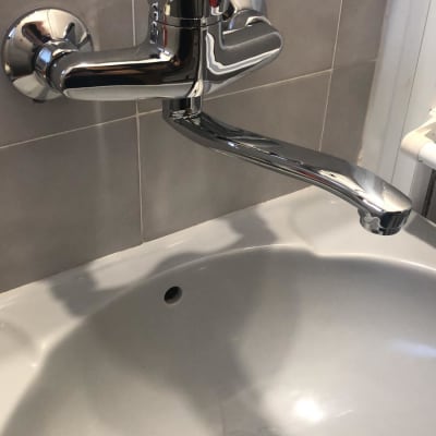 ברז כרום מותקן על קיר מעל כיור לבן