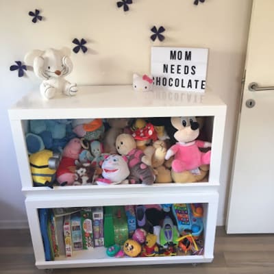 ארון צעצועים לבן עם מדפים מלאים בבובות וצעצועים