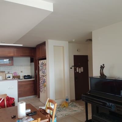 חדר עם פסנתר, צעצוע, ומטבח ברקע