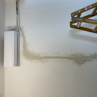 שקע חשמל על קיר ליד מזגן וסולם עץ