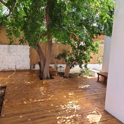 דק עץ בגינה עם עץ גדול וצל על הרצפה