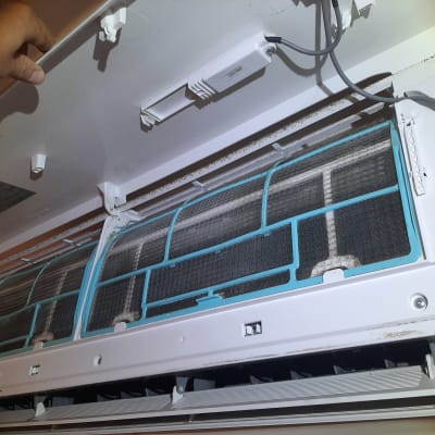 מסנן מזגן פתוח עם יד מחזיקה את הכיסוי