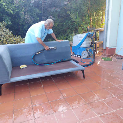 אדם מנקה ספה עם מכונת ניקוי בלחץ מים