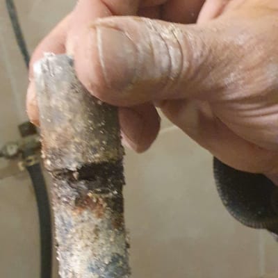 יד מחזיקה צינור חלוד עם נזילה