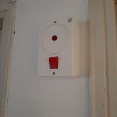 מתג חשמלי עם כפתור אדום על קיר לבן