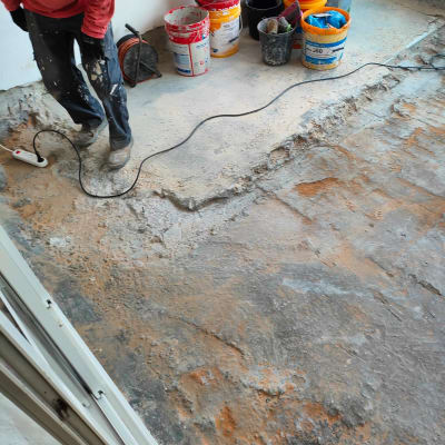 אדם עובד על רצפה עם דליים וחומרי איטום