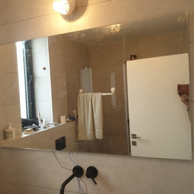 מראה גדולה בחדר אמבטיה עם השתקפות של דלת