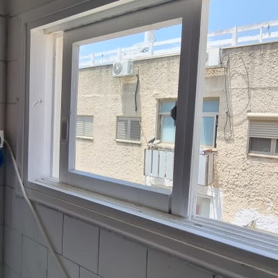 חלון זכוכית עם מסגרת לבנה וקיר חיצוני ברקע