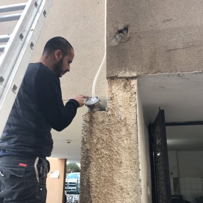 אדם מתקין צינור מיזוג אוויר על קיר חיצוני