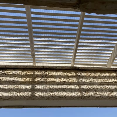 פרגולה מעץ עם קורות לבנות בשמש