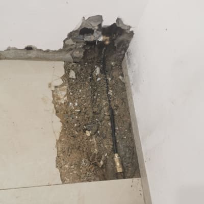 צינור מים חשוף בקיר שבור עם חיבורי מתכת