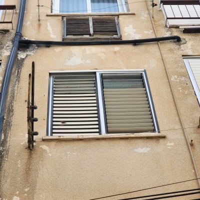 קיר חיצוני עם חלונות ותריסים, צינור מים על הקיר