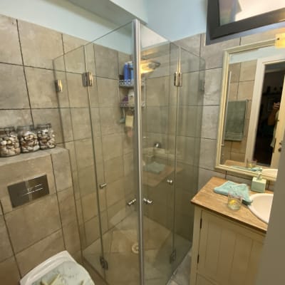 מקלחון זכוכית עם בקבוקי שמפו ומדף