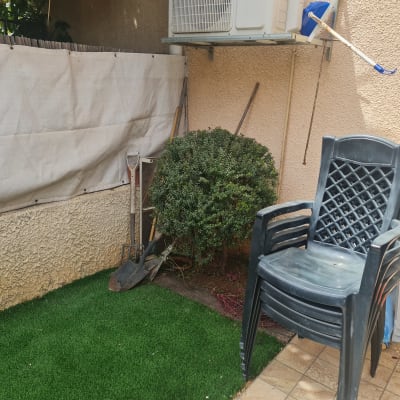 כלי גינון ליד שיח על דשא סינתטי