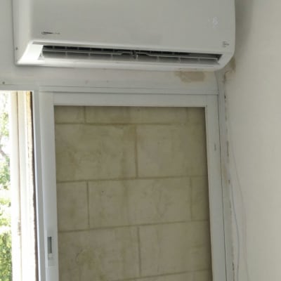 מזגן לבן מותקן מעל חלון קיר