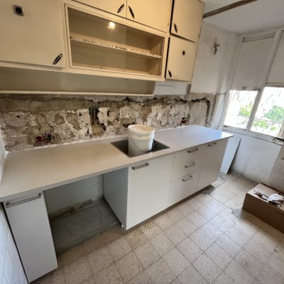 מטבח בשיפוץ עם ארונות, כיור ודלי צבע