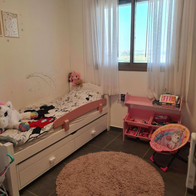 חדר ילדים עם מיטה, שטיח עגול וארגונית צעצועים