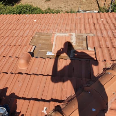 תיקון רעפים על גג עם צל אדם