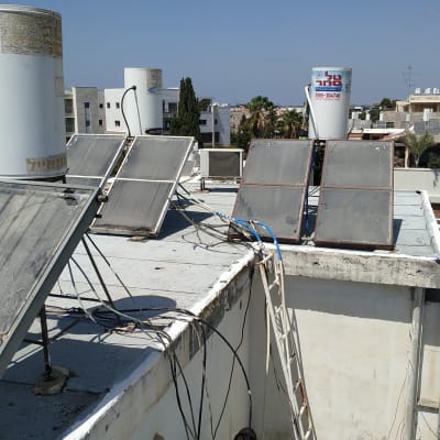 אדם עובד על גג עם לוחות סולאריים וצינורות