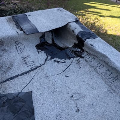 גג עם יריעות איטום קרועות ותיקונים באספלט שחור