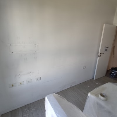 קיר לבן עם סימני צבע, דלי ומברשת צביעה