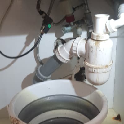 צנרת מתחת לכיור עם דלי מים