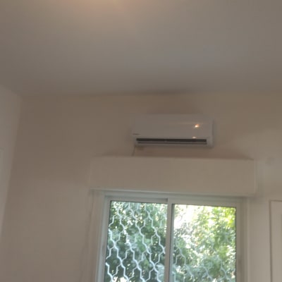 מזגן מותקן על קיר מעל חלון זכוכית