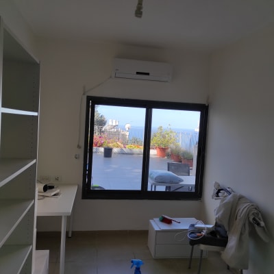 חדר עם מדפים, שולחן, חלון ומטאטא על כיסא