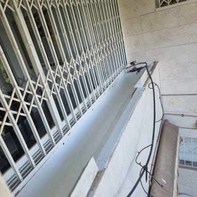 מרפסת עם סורגים, צינורות ואיטום על אדן החלון