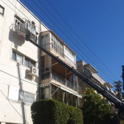 תריסים פתוחים במרפסת בניין עם מנוף