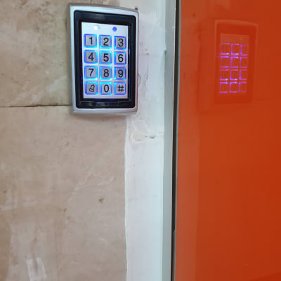 לוח מקשים מואר עם מספרים ליד דלת כתומה