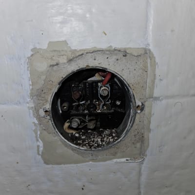 חיבורי חשמל חשופים בתוך קופסת חיבורים בקיר