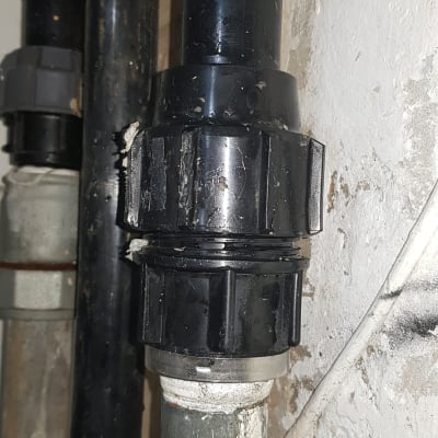 צינור שחור עם מחבר פלסטיק על קיר