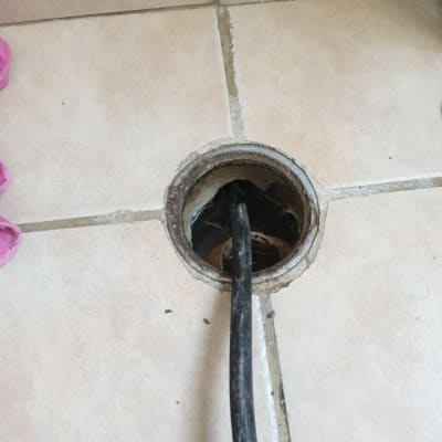 כבל שחור נכנס לניקוז ברצפה