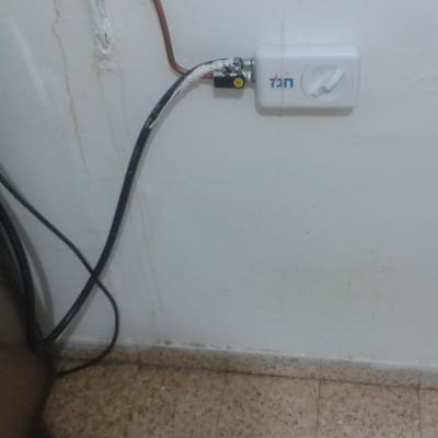 שסתום גז מחובר לצינור על קיר לבן